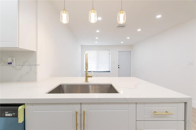 kitchen with visible vents, white cabinets, dishwashing machine, light stone counters, and a sink