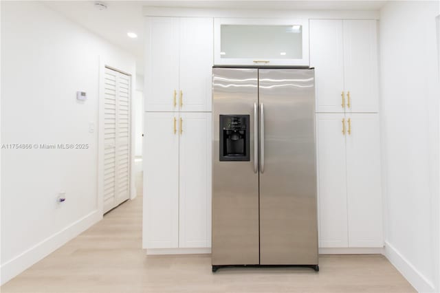 kitchen with light wood-style flooring, white cabinetry, baseboards, stainless steel fridge with ice dispenser, and glass insert cabinets