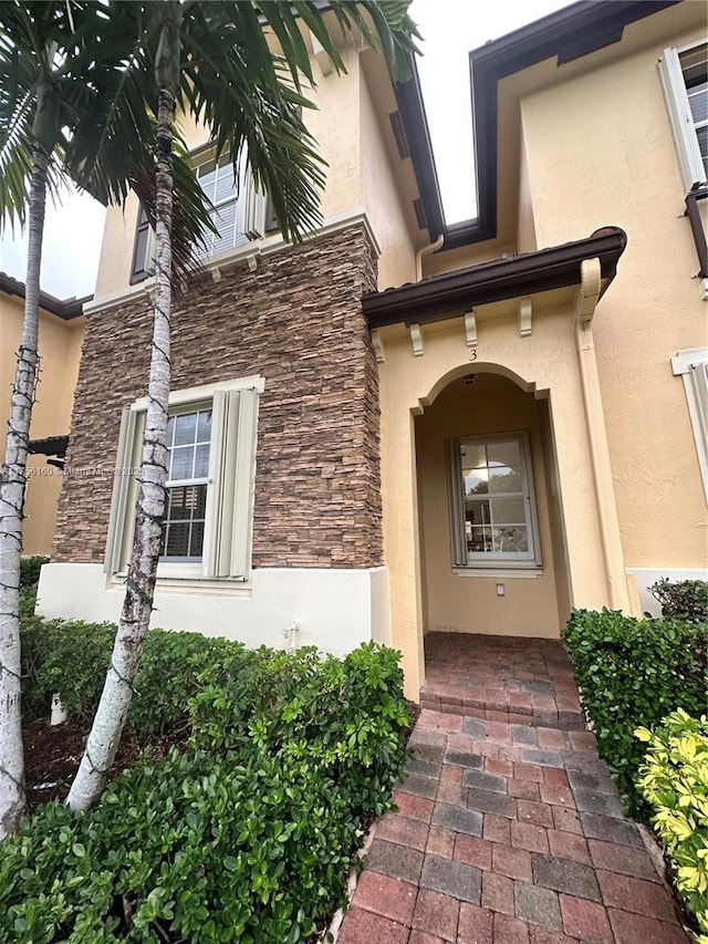 entrance to property featuring stone siding and stucco siding