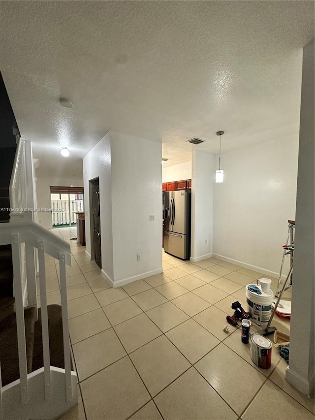 interior space with light tile patterned floors, stairs, visible vents, and a textured ceiling