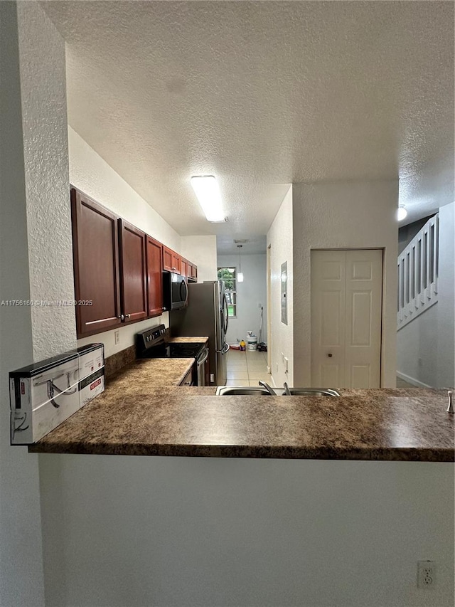 kitchen featuring a textured wall, stainless steel appliances, a textured ceiling, and dark countertops