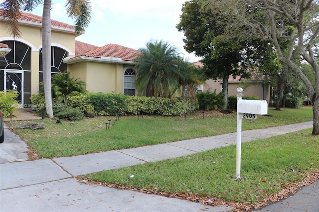 mediterranean / spanish-style home with a tiled roof, a front lawn, and stucco siding