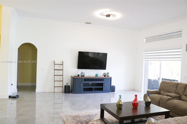 living room featuring arched walkways, ornamental molding, and baseboards