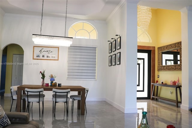 dining space with baseboards, a high ceiling, arched walkways, and ornamental molding