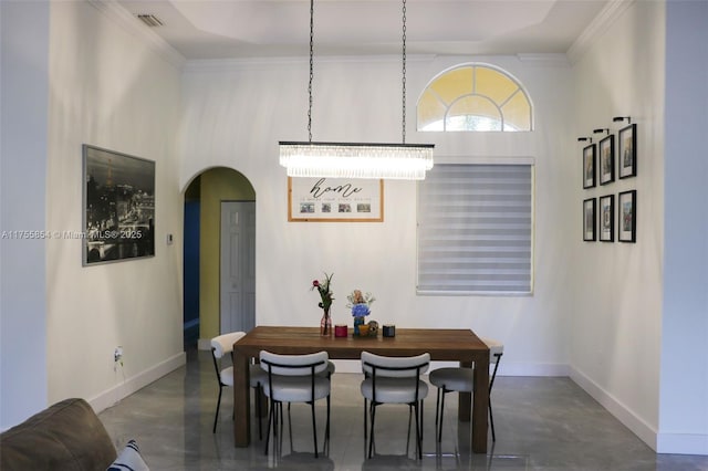 dining room featuring finished concrete flooring, baseboards, visible vents, arched walkways, and crown molding