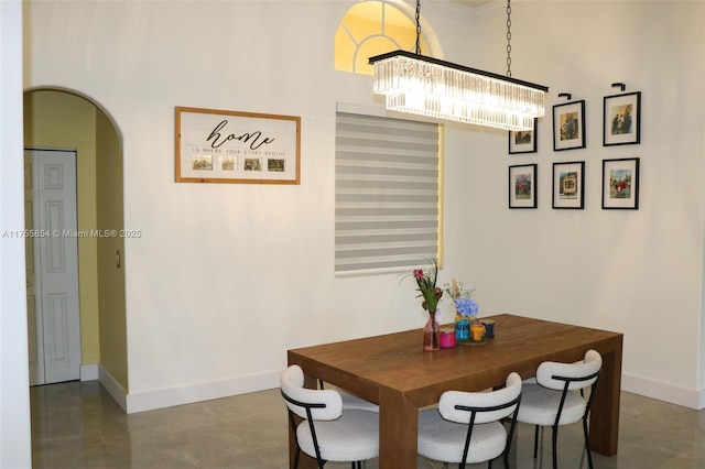 dining space featuring baseboards, arched walkways, and a chandelier