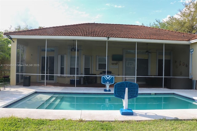 rear view of property featuring an outdoor pool, a sunroom, ceiling fan, a tiled roof, and a patio area