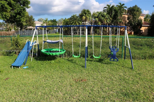 community jungle gym featuring fence and a lawn