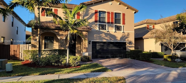 mediterranean / spanish-style home with a tiled roof, decorative driveway, and stucco siding