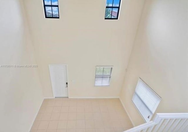 unfurnished room with a towering ceiling and baseboards