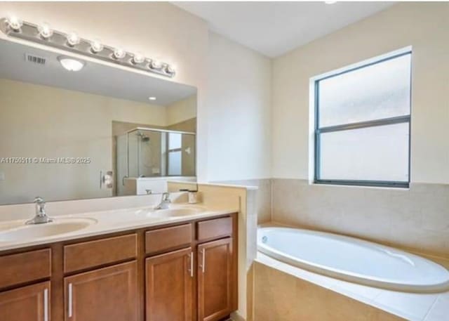 bathroom featuring a garden tub, double vanity, a sink, and a shower stall