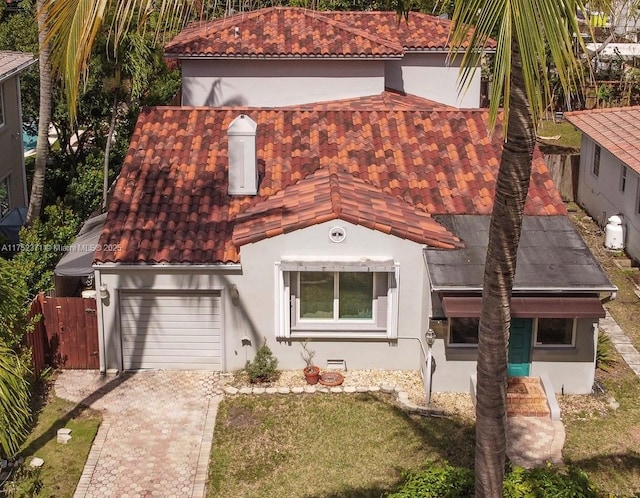 mediterranean / spanish-style house with an attached garage, a tile roof, concrete driveway, and stucco siding