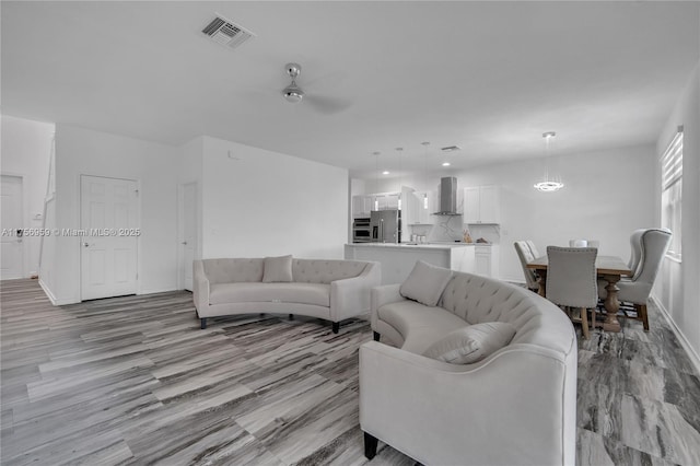 living area featuring visible vents, ceiling fan, and baseboards