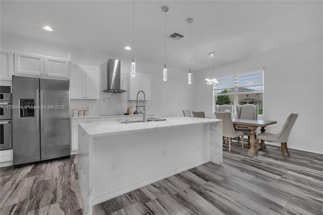 kitchen with stainless steel appliances, visible vents, white cabinets, a sink, and wall chimney exhaust hood