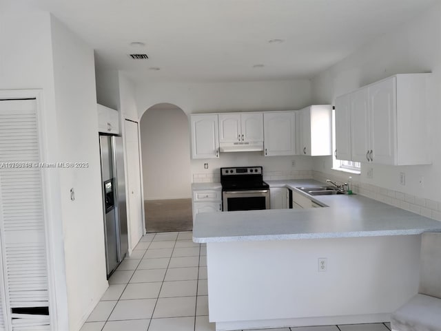 kitchen with arched walkways, a peninsula, stainless steel appliances, under cabinet range hood, and a sink