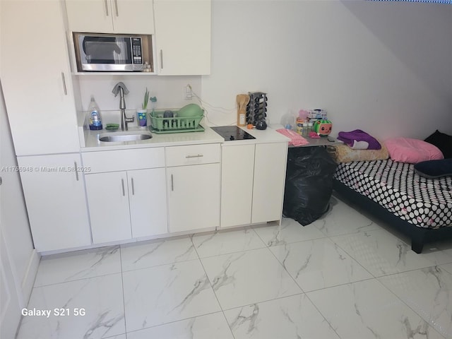 kitchen featuring a sink, light countertops, white cabinetry, stainless steel microwave, and marble finish floor