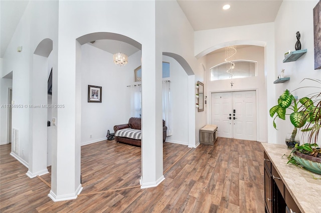 entryway featuring visible vents, a high ceiling, baseboards, and wood finished floors