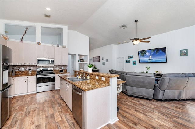 kitchen with stainless steel appliances, visible vents, open floor plan, a sink, and an island with sink