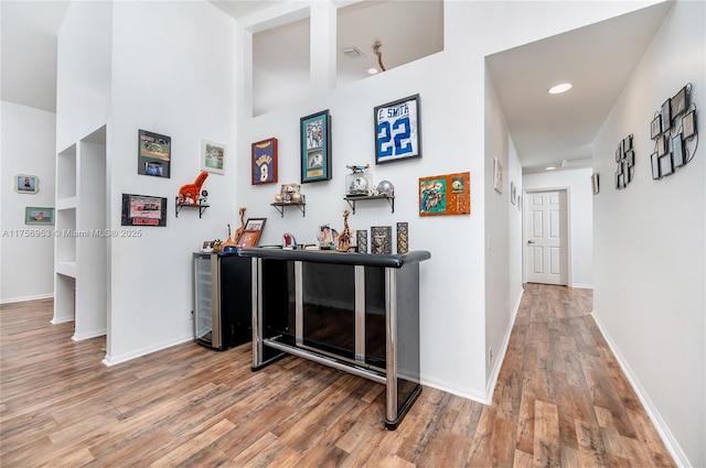 hallway featuring baseboards, wood finished floors, and recessed lighting