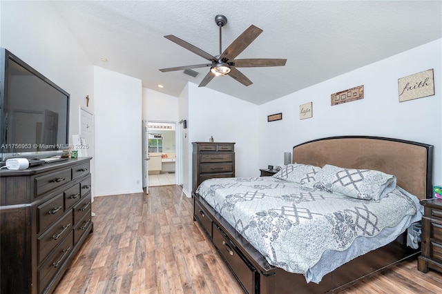 bedroom featuring a ceiling fan, lofted ceiling, light wood-style flooring, and a textured ceiling