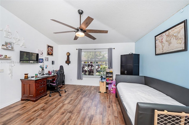 bedroom with lofted ceiling, a textured ceiling, wood finished floors, a ceiling fan, and baseboards