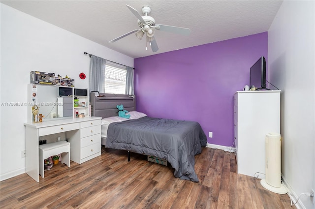 bedroom with a textured ceiling, wood finished floors, a ceiling fan, and baseboards