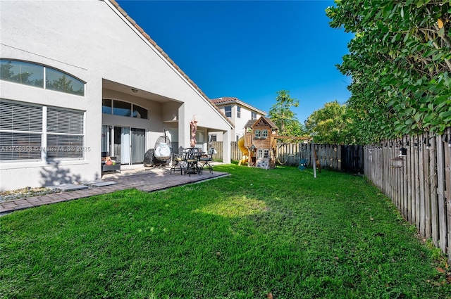 view of yard featuring a fenced backyard, a patio, and a playground