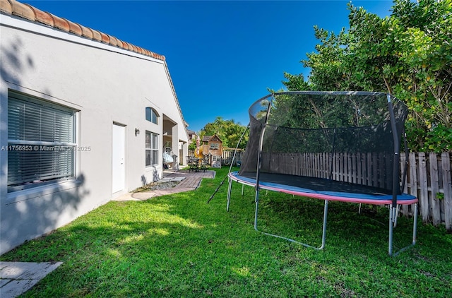 view of yard featuring fence and a trampoline