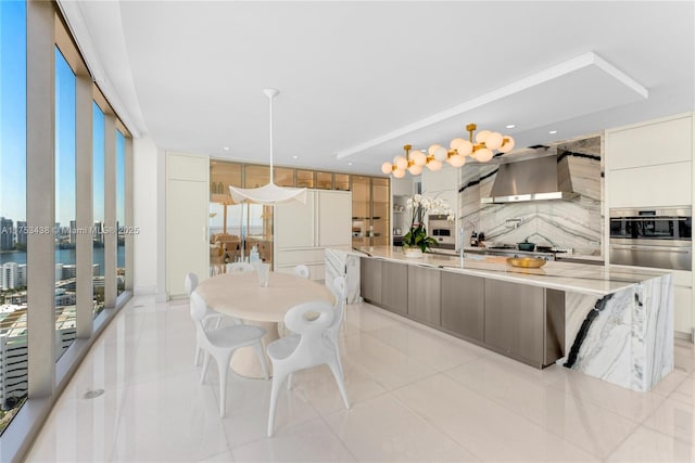 kitchen with floor to ceiling windows, decorative backsplash, appliances with stainless steel finishes, wall chimney range hood, and modern cabinets