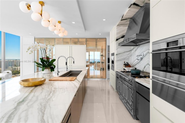 kitchen featuring wall chimney exhaust hood, a sink, a wealth of natural light, and floor to ceiling windows