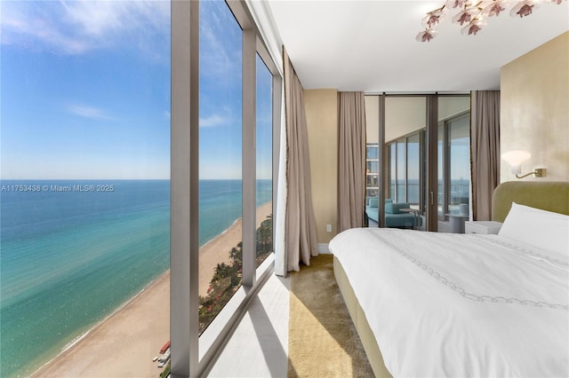 bedroom with a water view, floor to ceiling windows, and a view of the beach