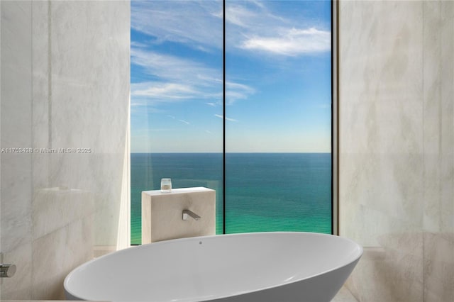 bathroom featuring a wall of windows, a soaking tub, tile walls, and a water view