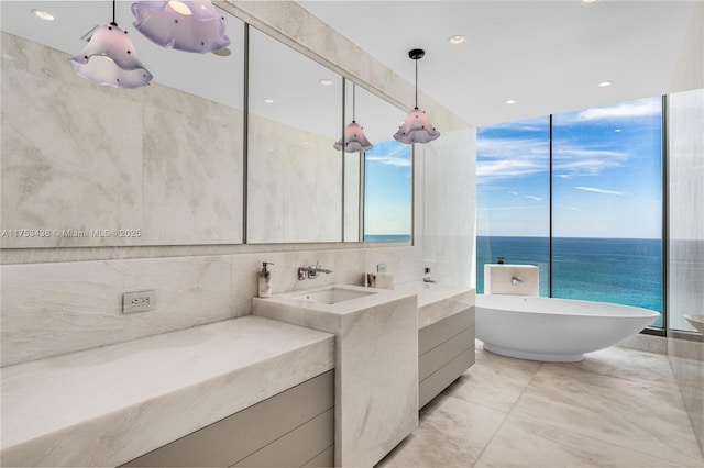 full bath featuring tile walls, a freestanding tub, and vanity