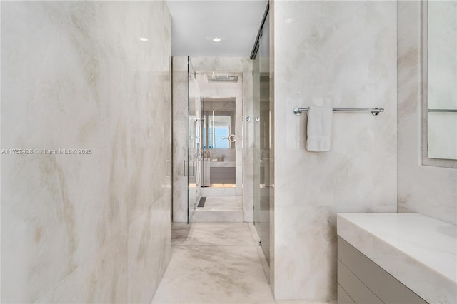 bathroom featuring a stall shower, tile walls, and vanity