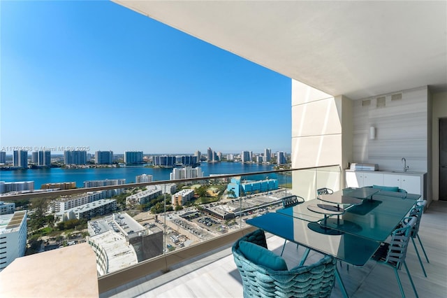 balcony featuring a view of city, a water view, a sink, and visible vents