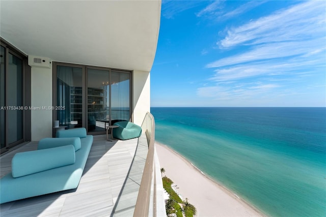 balcony with a water view, visible vents, and a beach view