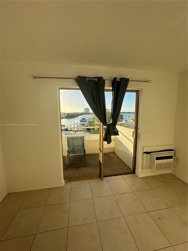 tiled spare room featuring an AC wall unit and baseboards