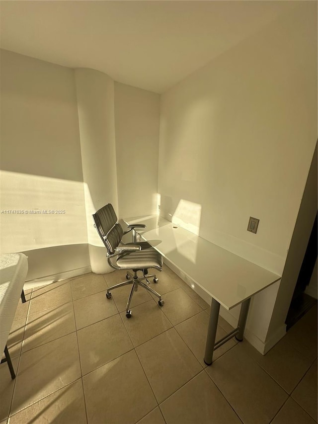 unfurnished office featuring baseboards and tile patterned floors