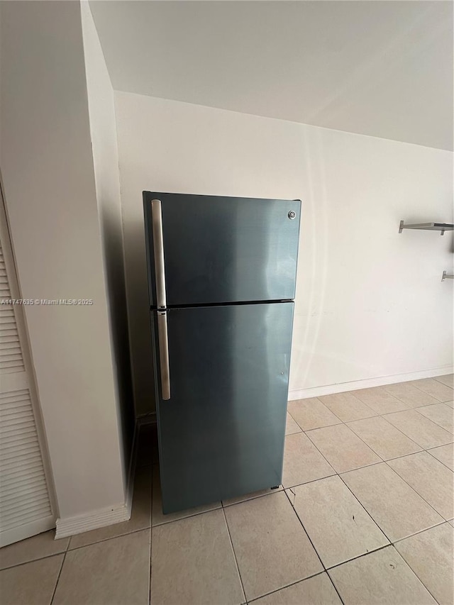 kitchen featuring light tile patterned floors, freestanding refrigerator, and baseboards