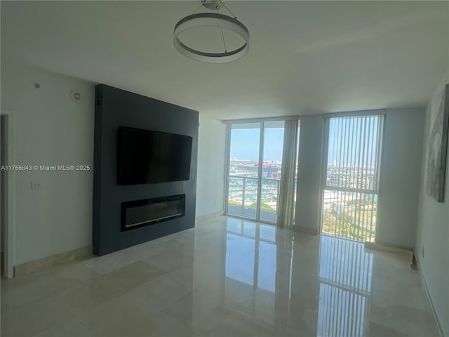 unfurnished living room featuring light tile patterned floors, baseboards, and a wall of windows