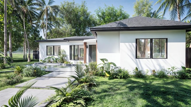 view of front of house with a shingled roof, a front yard, and stucco siding