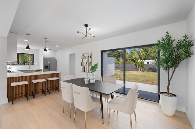 dining space featuring light wood-type flooring, a wealth of natural light, an inviting chandelier, and recessed lighting