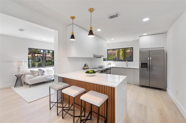 kitchen with stainless steel fridge, visible vents, modern cabinets, a peninsula, and light countertops