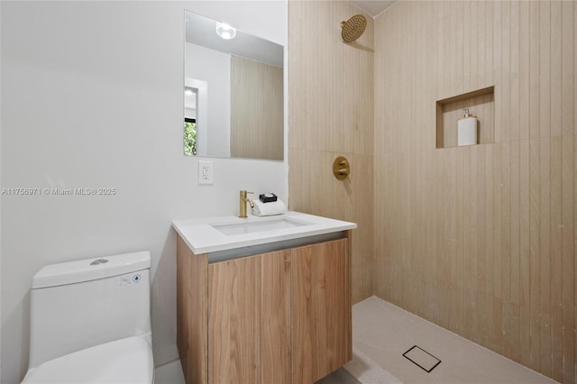 full bathroom featuring a tile shower, vanity, and toilet