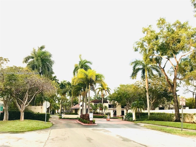 view of property's community with driveway, fence, and a lawn