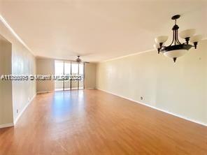 unfurnished room featuring a wall of windows, baseboards, and wood finished floors