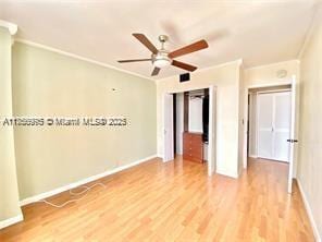 empty room with baseboards, ceiling fan, ornamental molding, and light wood-style floors