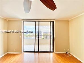 empty room with expansive windows, baseboards, wood finished floors, and crown molding