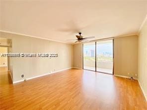 empty room with baseboards, floor to ceiling windows, ornamental molding, and wood finished floors