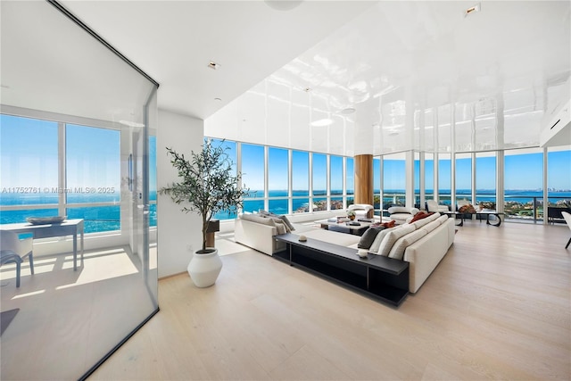 living room with expansive windows, a water view, and wood finished floors